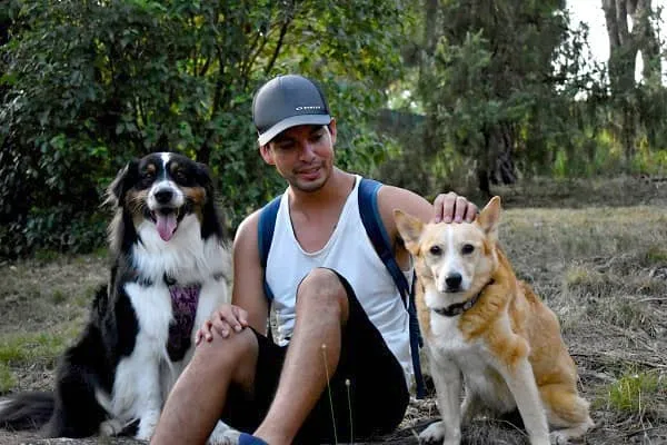 Alexis assis entre ses deux chiens Amé et Fiona